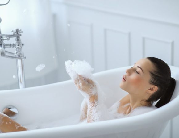 young nude woman taking relaxing foamy bath min 1