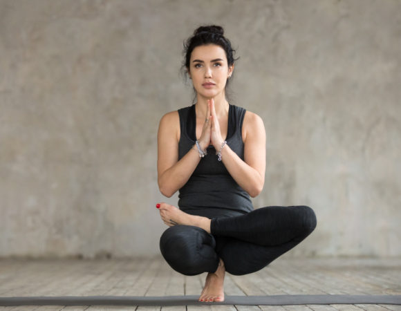 young woman doing half lotus toe balance exercise