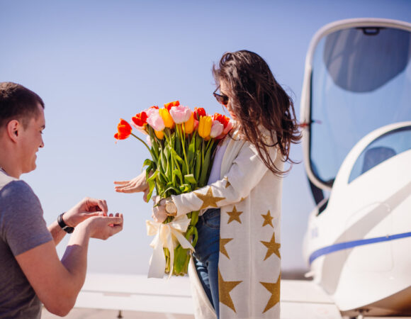 man makes proposal woman standing before airplane