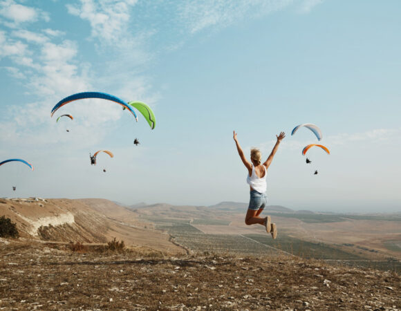 young blonde woman jumping top hill